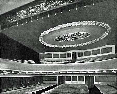Photograph of a cinema auditorium ceiling: a large oval painting ringed by a circle of lights, with the balcony and seating below